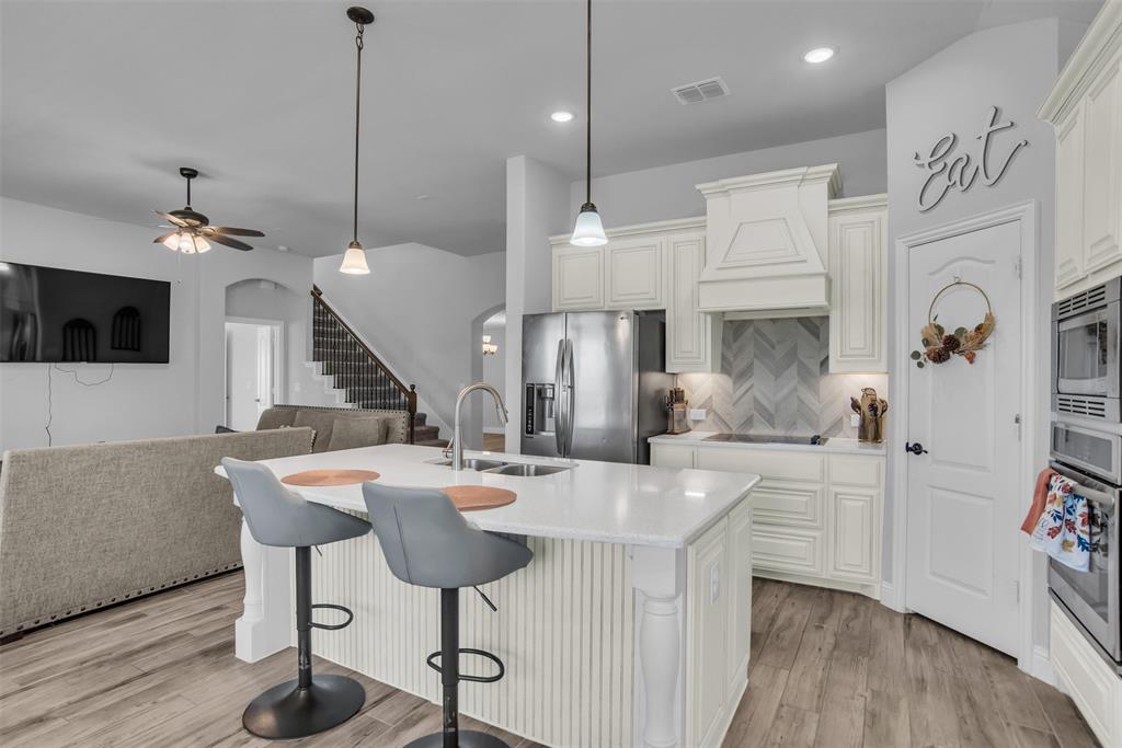 1566 Harrison Circle Waxahachie, TX 75165 - Photo 25 of 38 a kitchen with stainless steel appliances kitchen island granite countertop a table chairs and a wooden floor