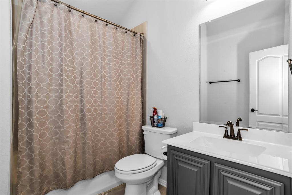 1566 Harrison Circle Waxahachie, TX 75165 - Photo 32 of 38 a bathroom with a sink a toilet a mirror and shower curtain