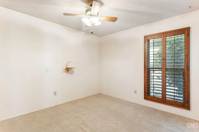 an empty room with windows and fan