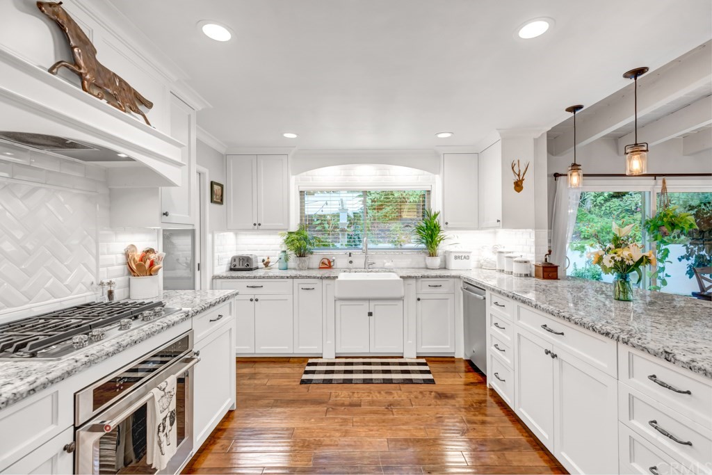 2601 Sunnyside Ridge Road Rancho Palos Verdes, CA 90275 - Photo 13 of 47 a large white kitchen with stainless steel appliances granite countertop a stove a sink dishwasher and white cabinets with wooden floor