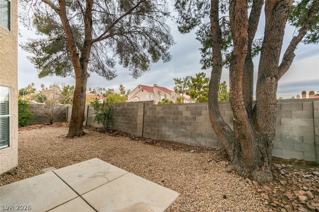 1738 Toltec Circle Henderson, NV 89014 - Photo 18 of 46 A tranquil desert backyard awaits, featuring mature trees and a sturdy block fence for privacy.