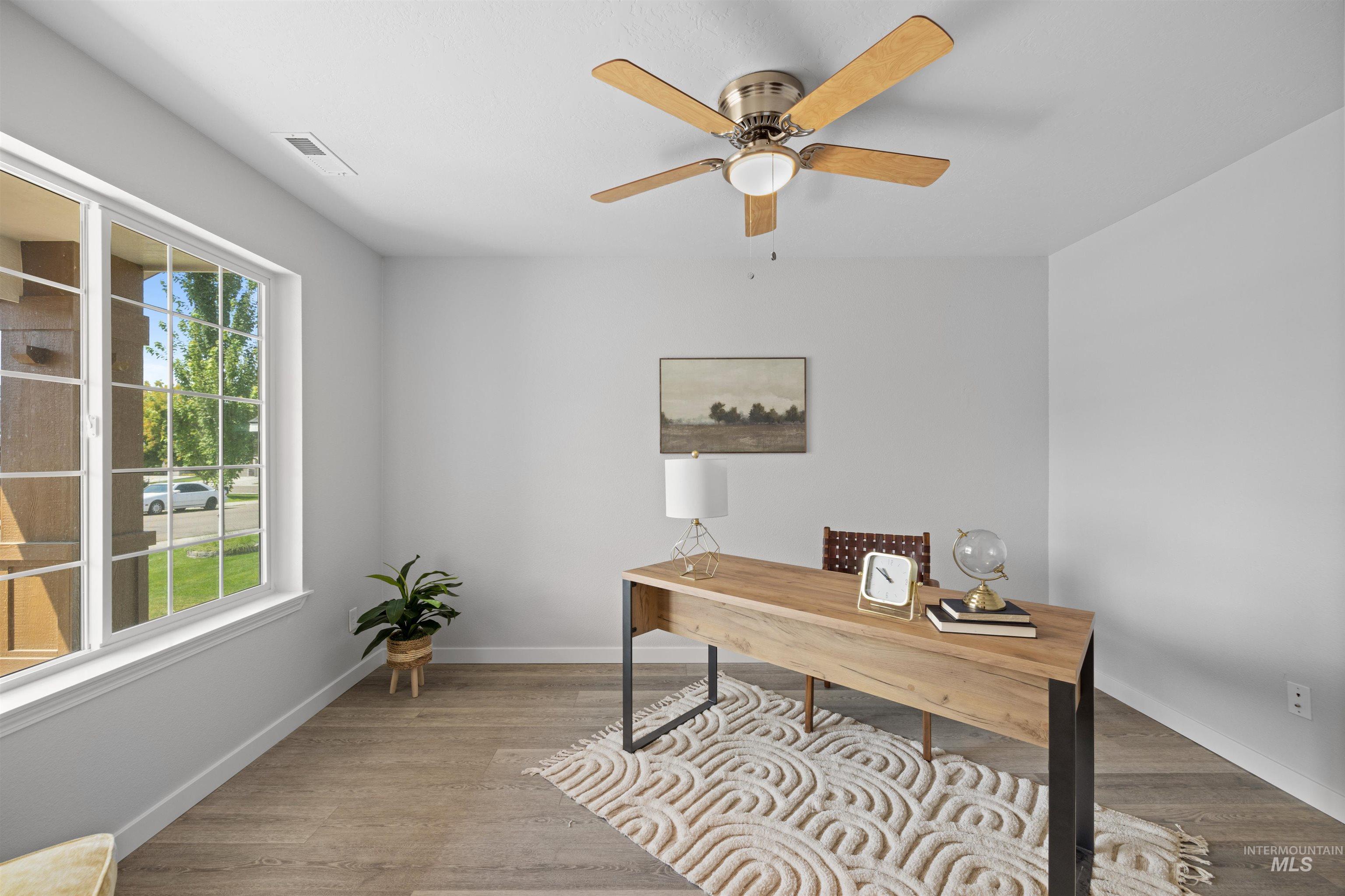 300 South Rocker Avenue Kuna, ID 83634 - Photo 5 of 49 Spacious room featuring wood-finish flooring, a large window, light-toned walls, a ceiling fan with integrated lighting, and white trim