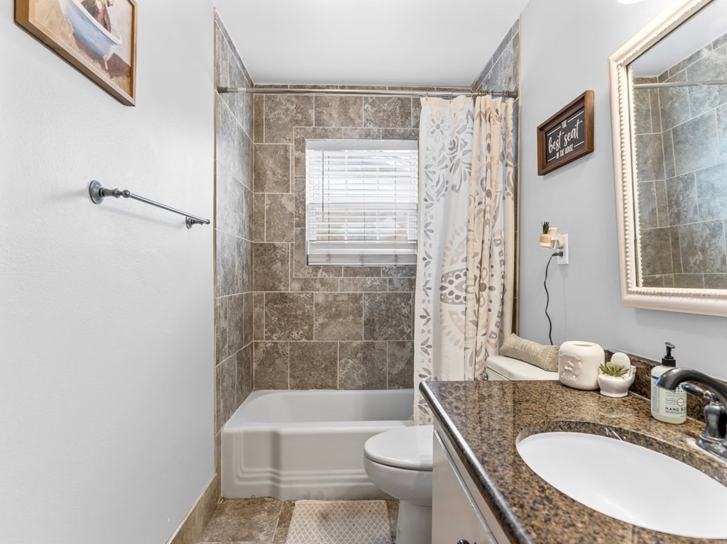 4009 Rice Avenue Bay City, TX 77414 - Photo 15 of 26 a bathroom with a granite countertop sink toilet a mirror a bathtub and shower