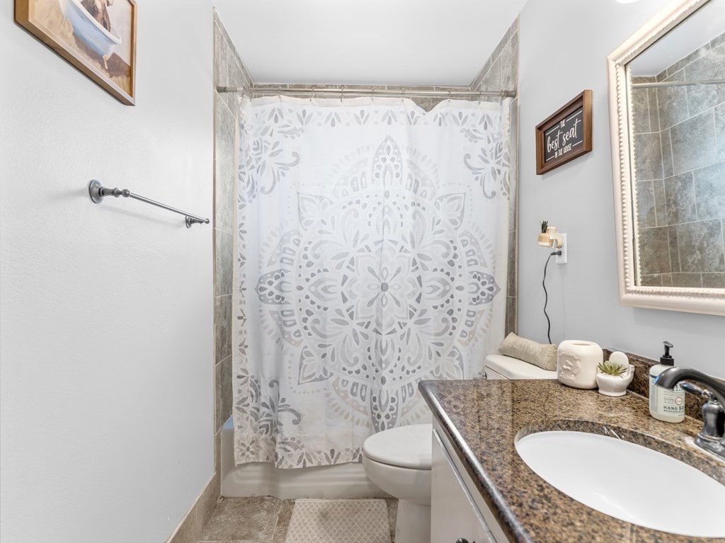 4009 Rice Avenue Bay City, TX 77414 - Photo 16 of 26 a bathroom with a granite countertop sink toilet a mirror a vanity and shower
