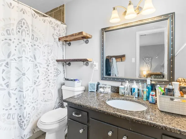 a bathroom with a granite countertop sink mirror vanity and toilet