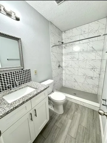 a bathroom with a granite countertop sink toilet and shower