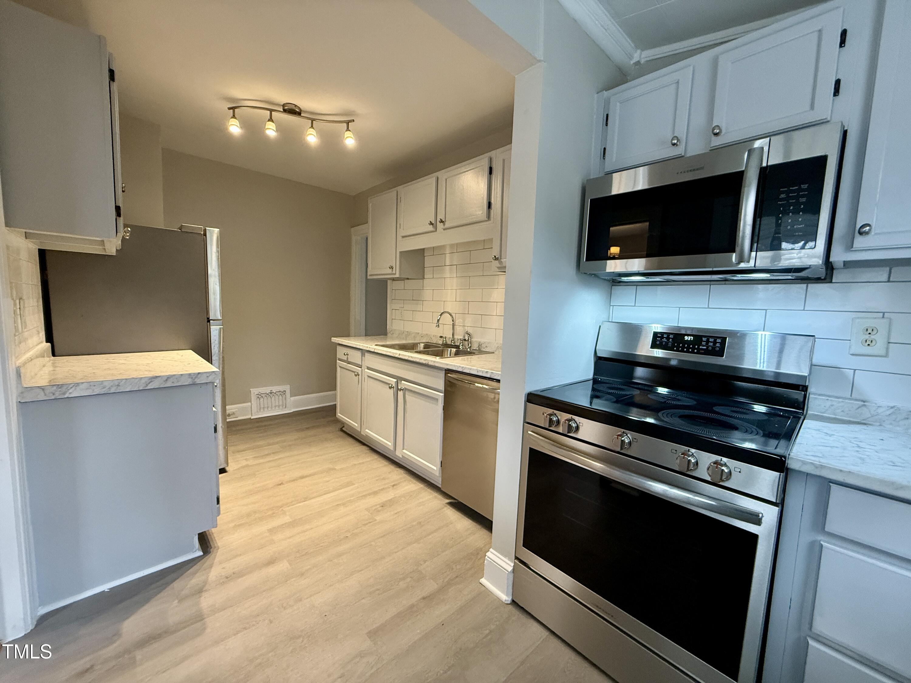 2409 Shenandoah Avenue Durham, NC 27704 - Photo 11 of 31 a kitchen with stainless steel appliances a stove a microwave a sink and cabinets