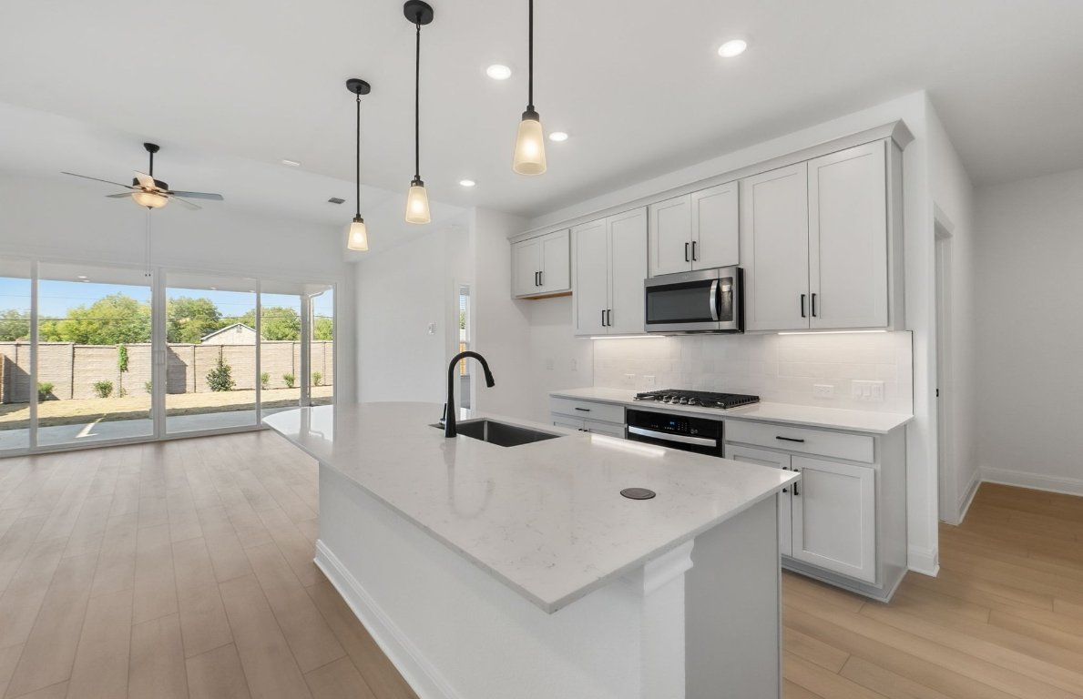 217 Regatta Trail Leander, TX 78641 - Photo 5 of 28 a kitchen with kitchen island a stove a sink and wooden floor