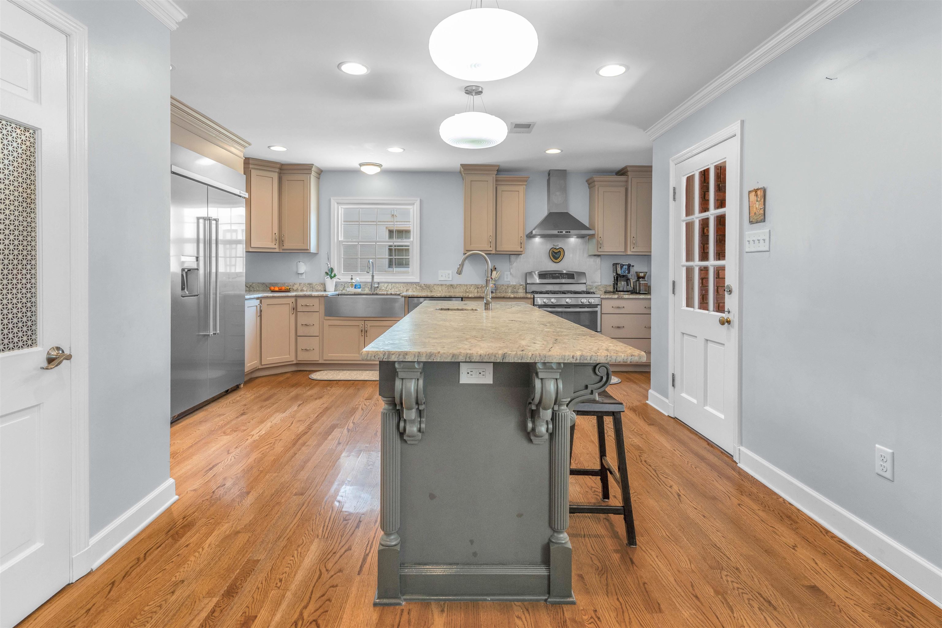 5187 South Angela Road Memphis, TN 38117 - Photo 11 of 39 Spacious kitchen featuring a large central island with decorative corbels, wood-finish flooring, stainless steel appliances, a farmhouse sink, and ample cabinetry