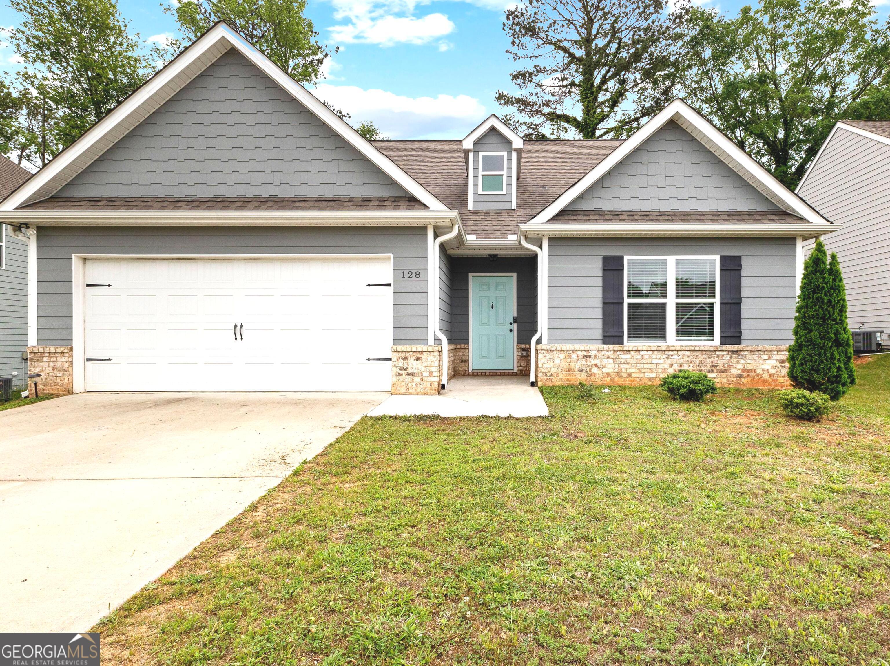 128 Savannah Way Milner, GA 30257 - Photo 1 of 1 a view of a white house with a yard plants and large tree