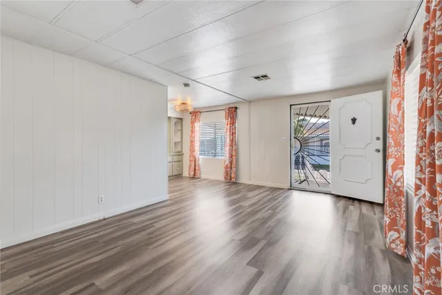 a view of a big room with wooden floor and windows