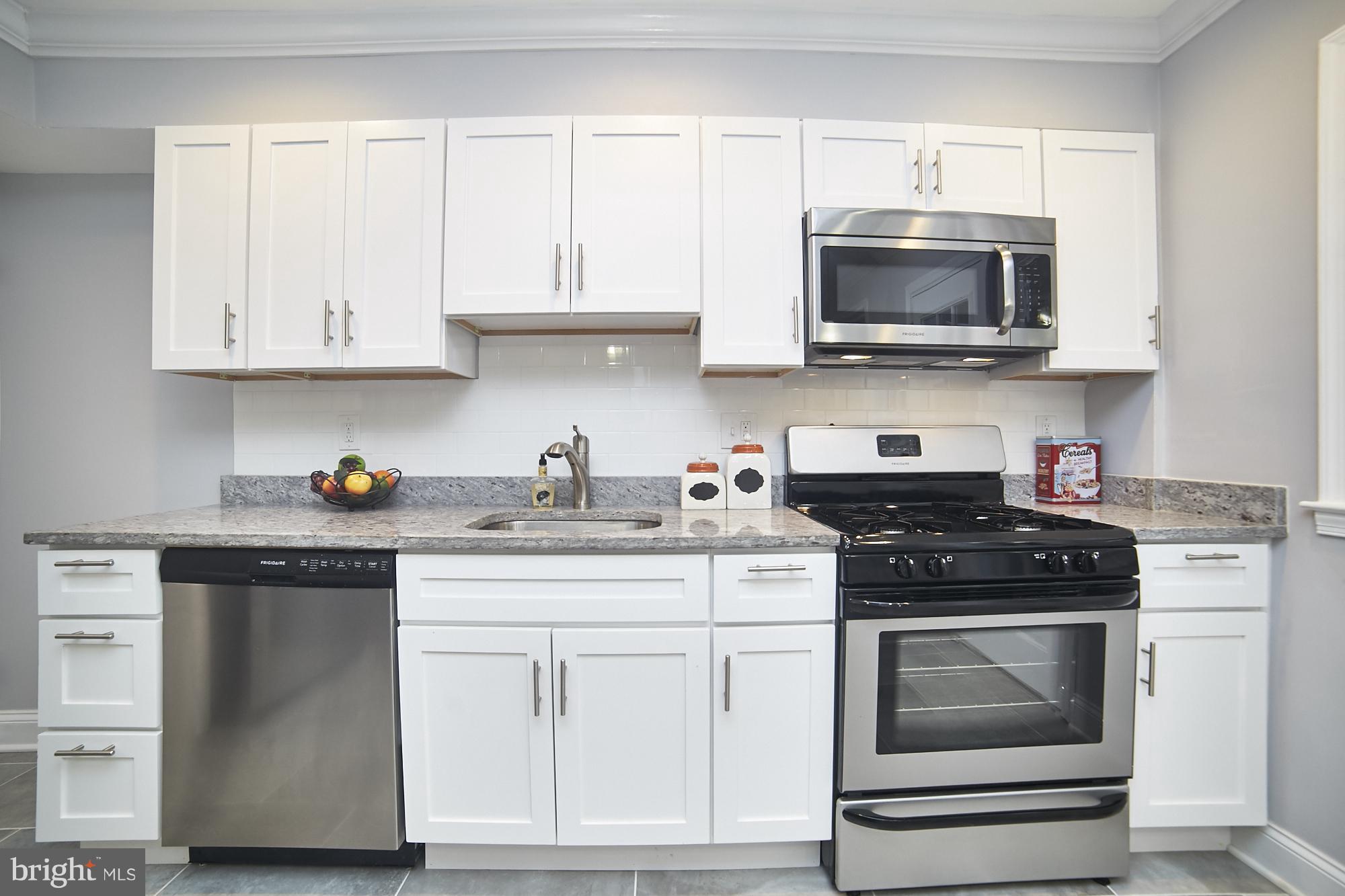 3814 Elkader Road Baltimore, MD 21218 - Photo 9 of 30 a kitchen with white cabinets and stainless steel appliances