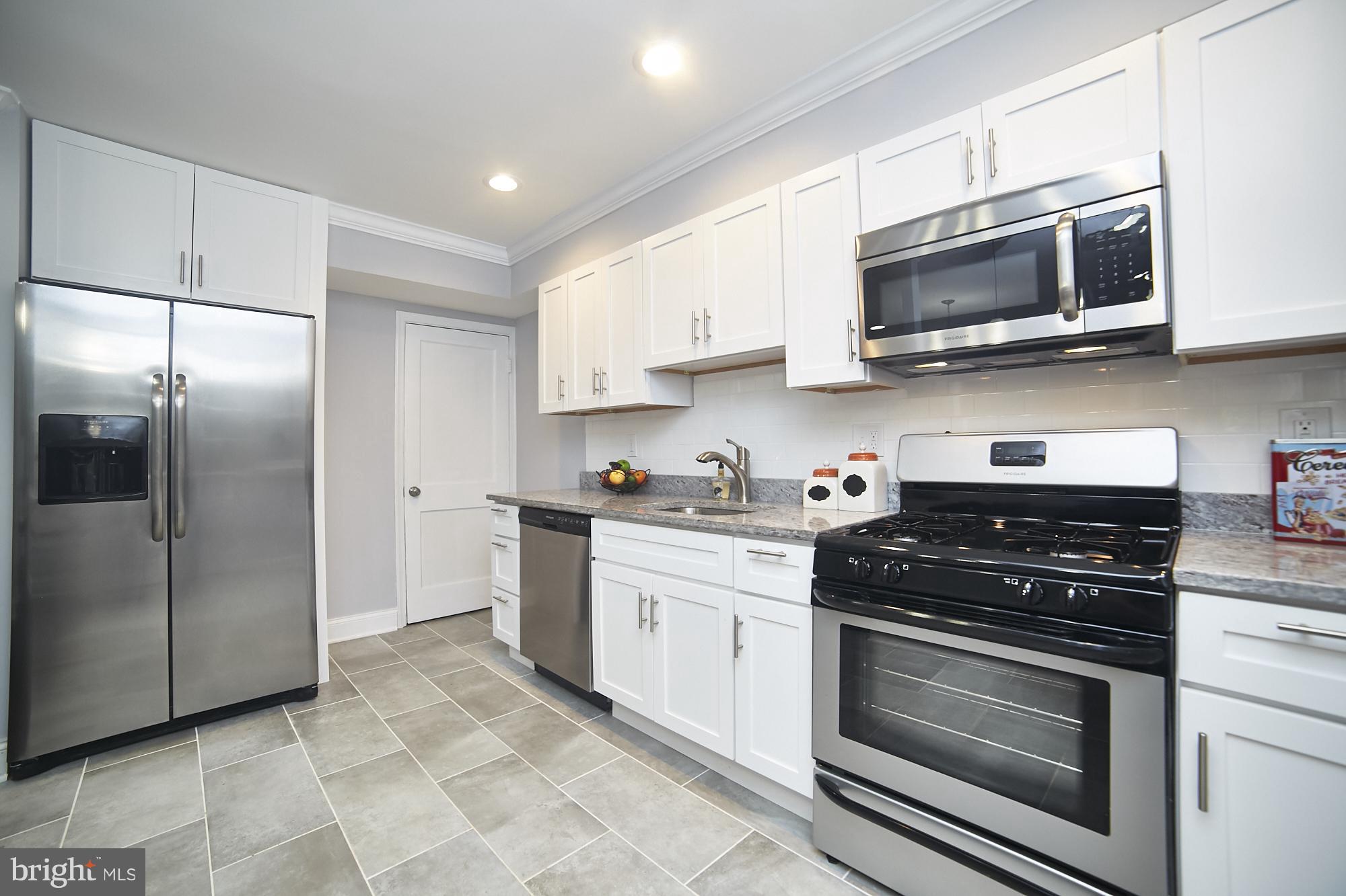 3814 Elkader Road Baltimore, MD 21218 - Photo 10 of 30 a kitchen with stainless steel appliances granite countertop a stove a microwave and a refrigerator