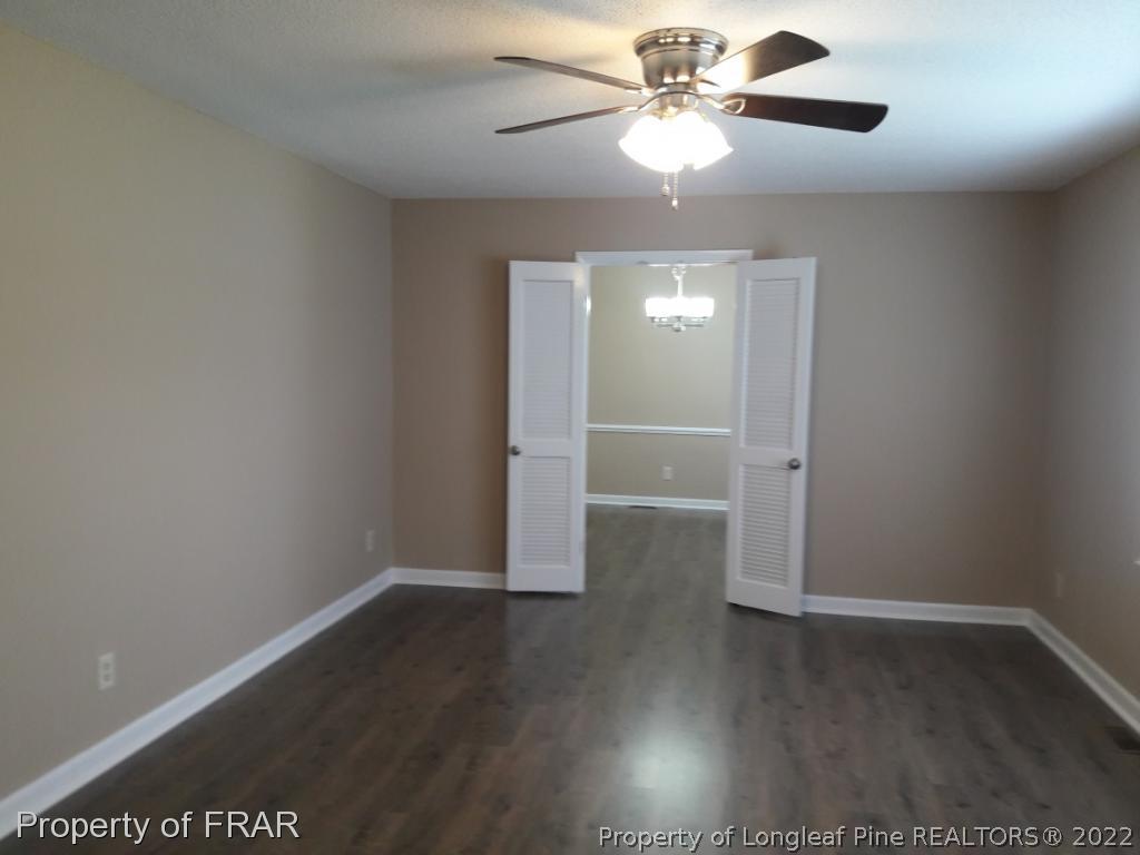 821 Bedford Road Fayetteville, NC 28303 - Photo 6 of 14 an empty room with wooden floor chandelier fan and closet area