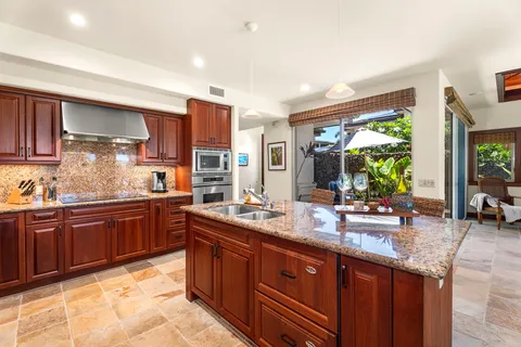 a large kitchen with kitchen island granite countertop wooden cabinets a granite counter tops and a large window