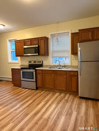 a kitchen with stainless steel appliances granite countertop a stove a sink dishwasher a refrigerator and a microwave oven with wooden floor