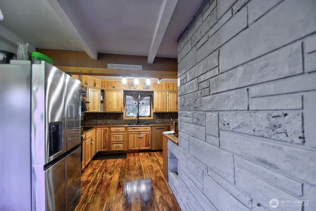 a kitchen with stainless steel appliances cabinets a large window and wooden floor