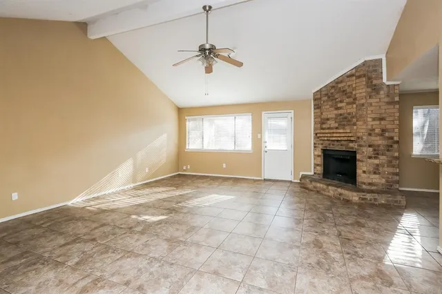 an empty room with windows and fireplace