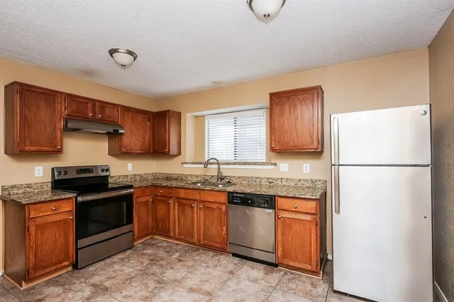 a kitchen with stainless steel appliances granite countertop a stove a sink dishwasher and a refrigerator