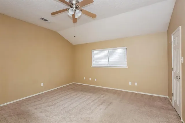 an empty room with chandelier fan and windows