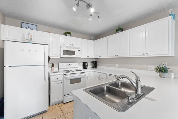 a kitchen with a sink a white refrigerator and white cabinets