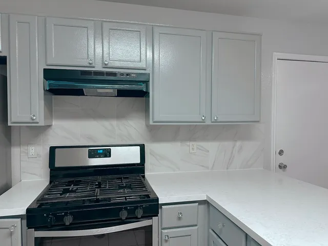 a kitchen with white cabinets and a stove top oven