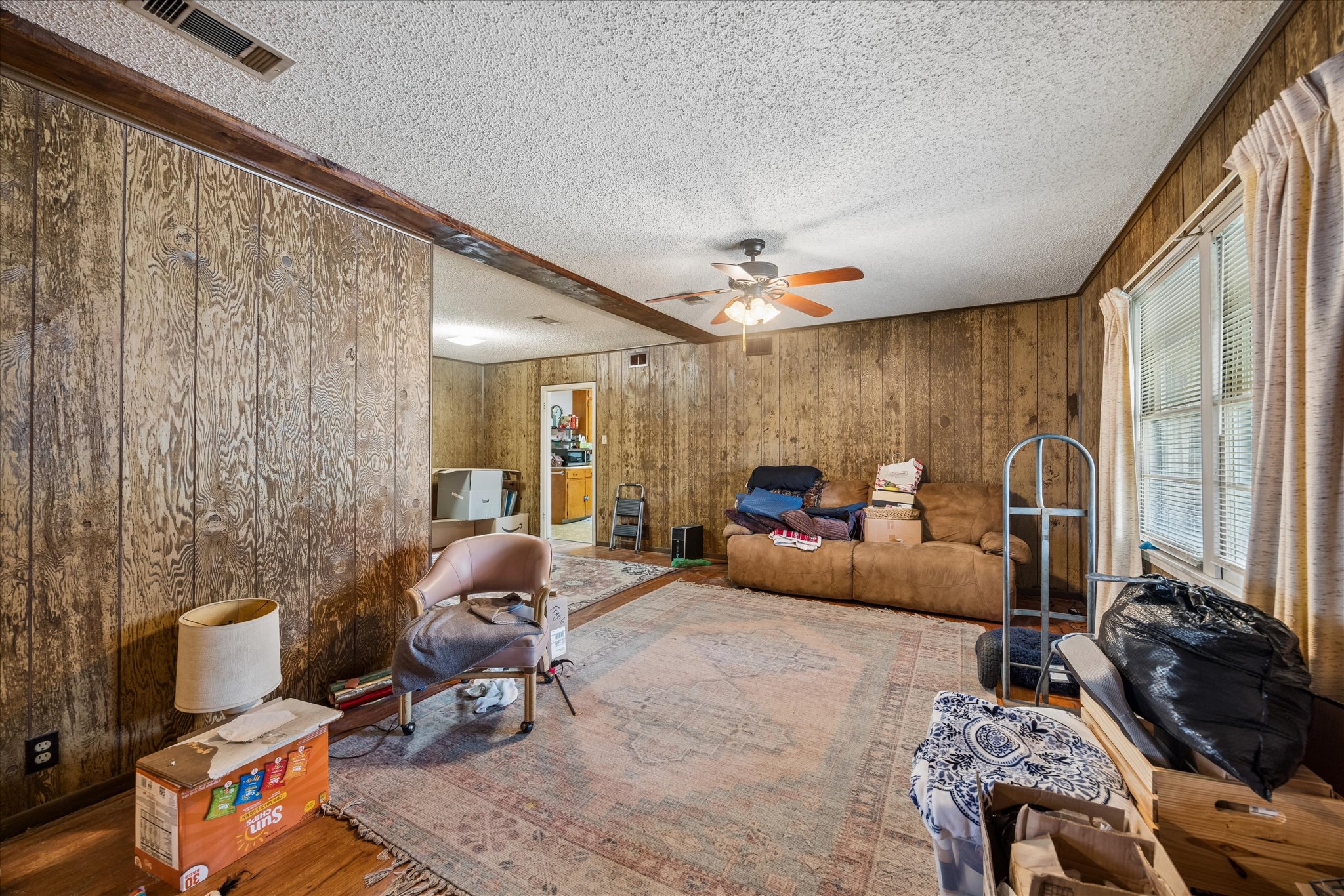 2009 Fort View Road Austin, TX 78704 - Photo 12 of 40 A welcoming living area boasts a ceiling fan, wood-paneled walls, and warm natural light.