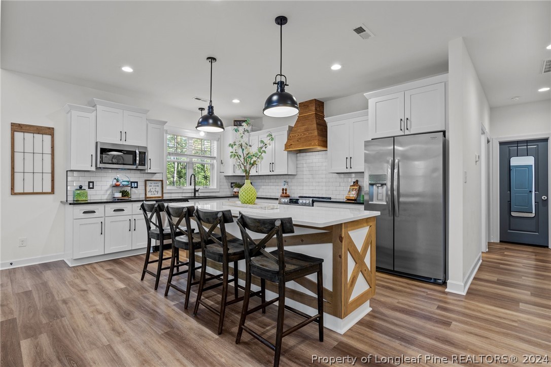 15420 Raccoon Run Road Wagram, NC 28396 - Photo 6 of 39 a kitchen with stainless steel appliances granite countertop a refrigerator a stove top oven a sink dishwasher and a dining table with wooden floor