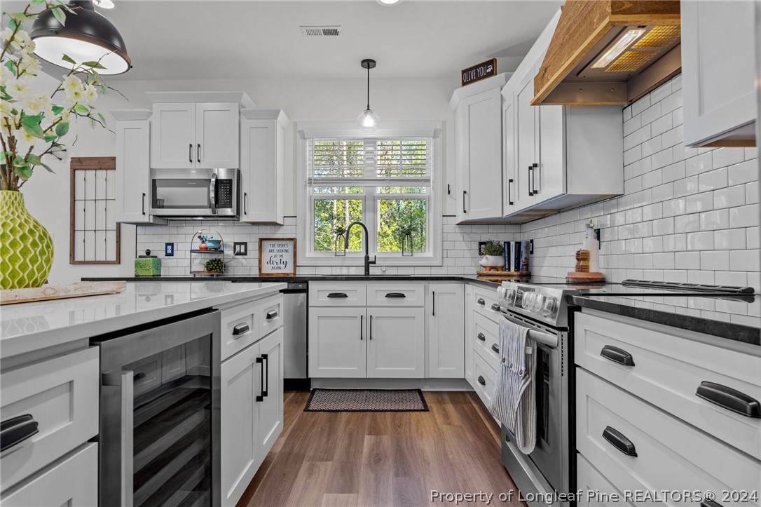 15420 Raccoon Run Road Wagram, NC 28396 - Photo 8 of 39 a kitchen with stainless steel appliances granite countertop a stove a sink dishwasher and white cabinets with wooden floor