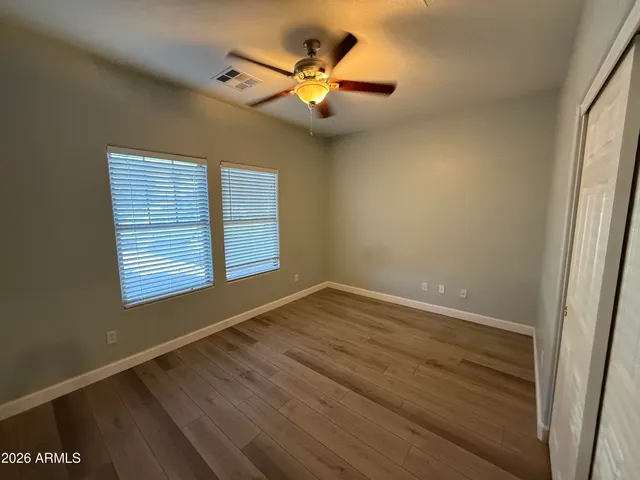 an empty room with wooden floor and windows