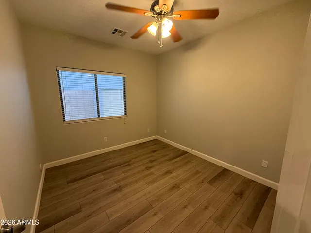 en empty room with wooden floor and fan