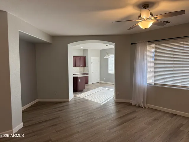 a view of an empty room with window wooden floor and a kitchen