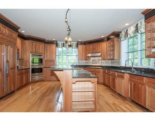 a kitchen with stainless steel appliances granite countertop a refrigerator a sink dishwasher a stove and a dining table with wooden floor