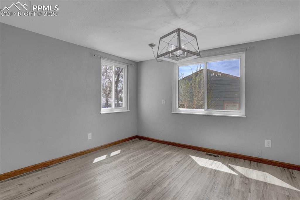 1024 Prairie Road Colorado Springs, CO 80909 - Photo 8 of 22 a view of a bedroom with wooden floor chandelier and windows