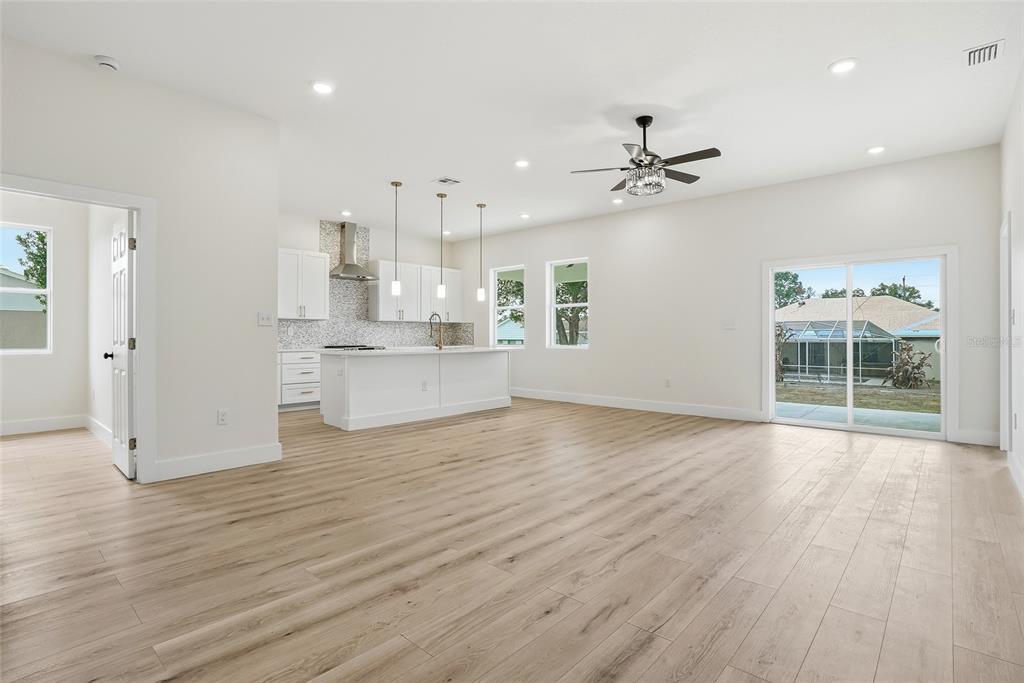 11256 Salters Street Spring Hill, FL 34609 - Photo 13 of 46 an empty room with wooden floor kitchen view and windows