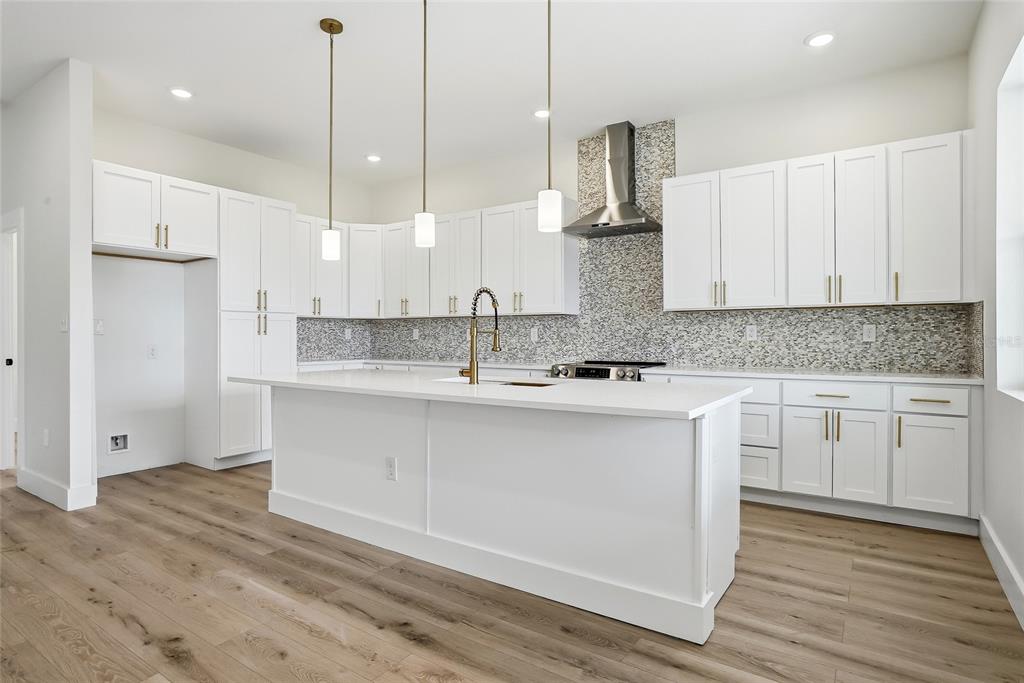 11256 Salters Street Spring Hill, FL 34609 - Photo 15 of 46 a kitchen with stainless steel appliances granite countertop a sink a stove a refrigerator and white cabinets with wooden floor