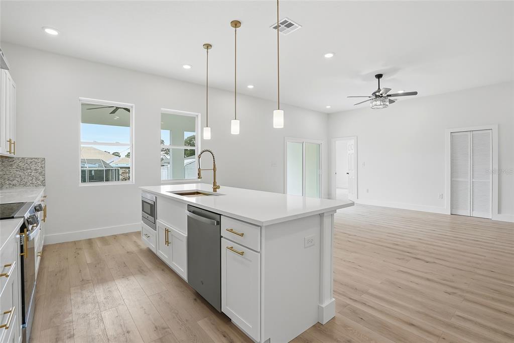 11256 Salters Street Spring Hill, FL 34609 - Photo 17 of 46 a kitchen with a stove a sink a window and wooden floor
