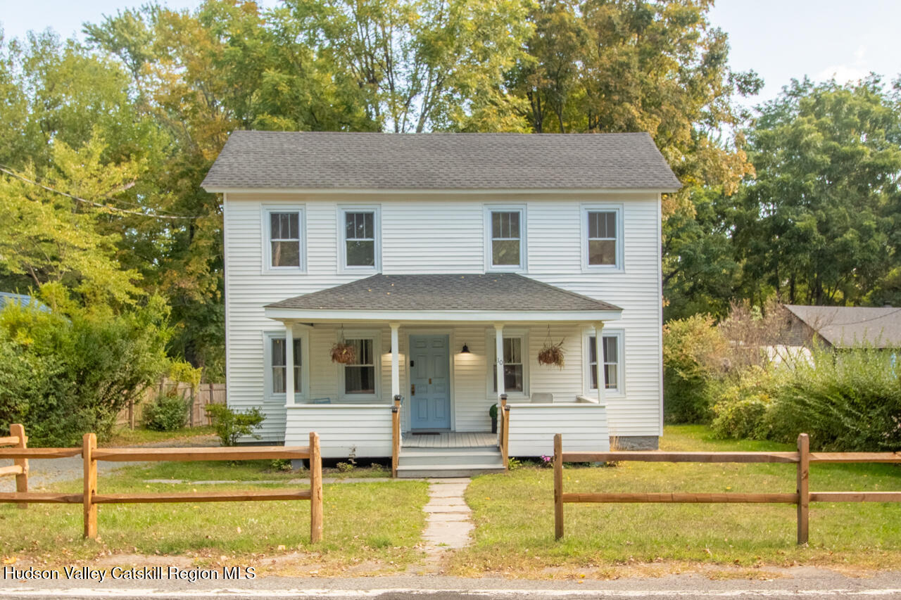 a view of a white house with large windows and a table and chairs under an umbrella