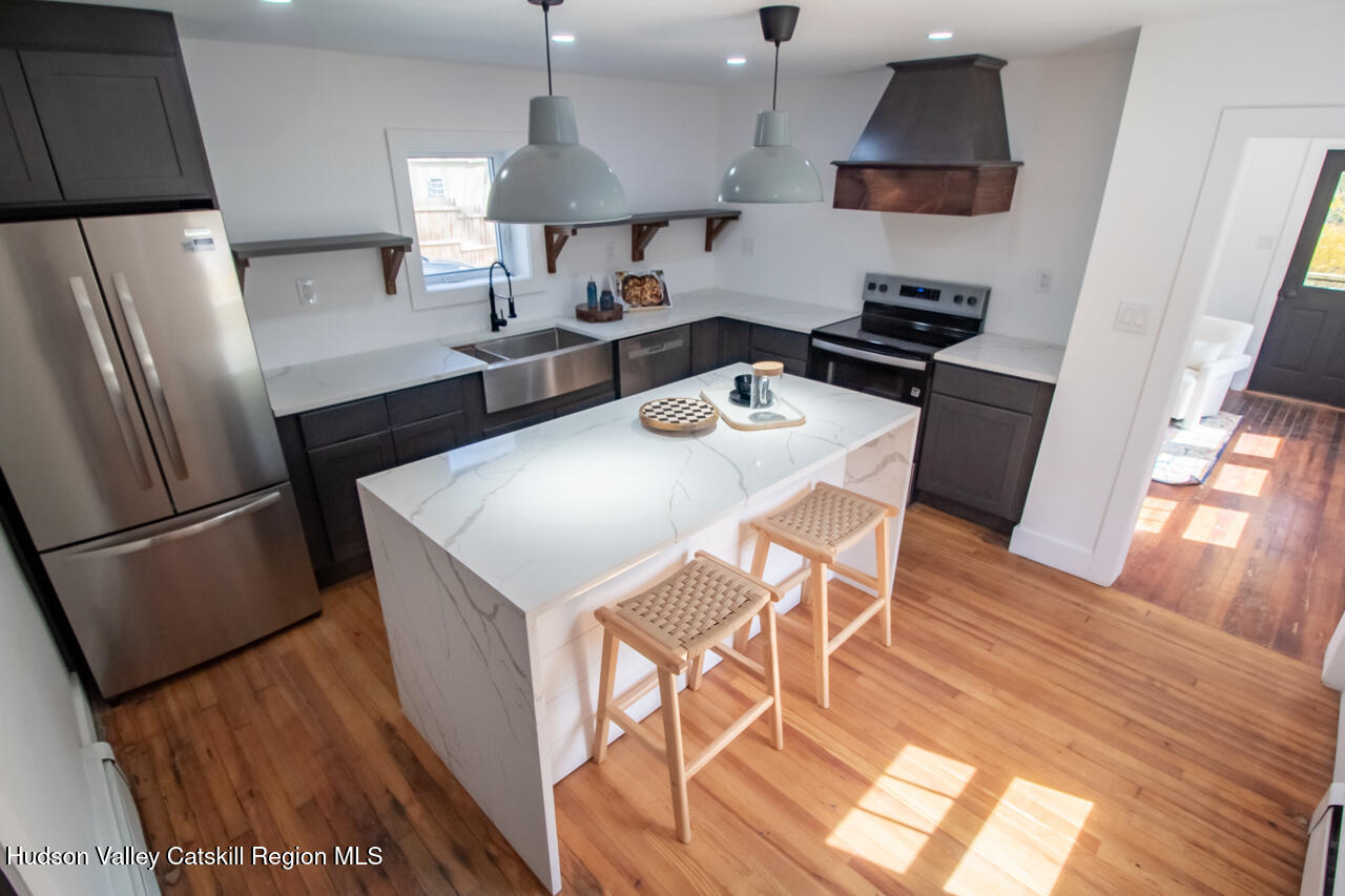 10 State Rte 55 Napanoch, NY 12458 - Photo 19 of 42 a kitchen with stainless steel appliances a stove a refrigerator a sink a dining table and chairs with wooden floor