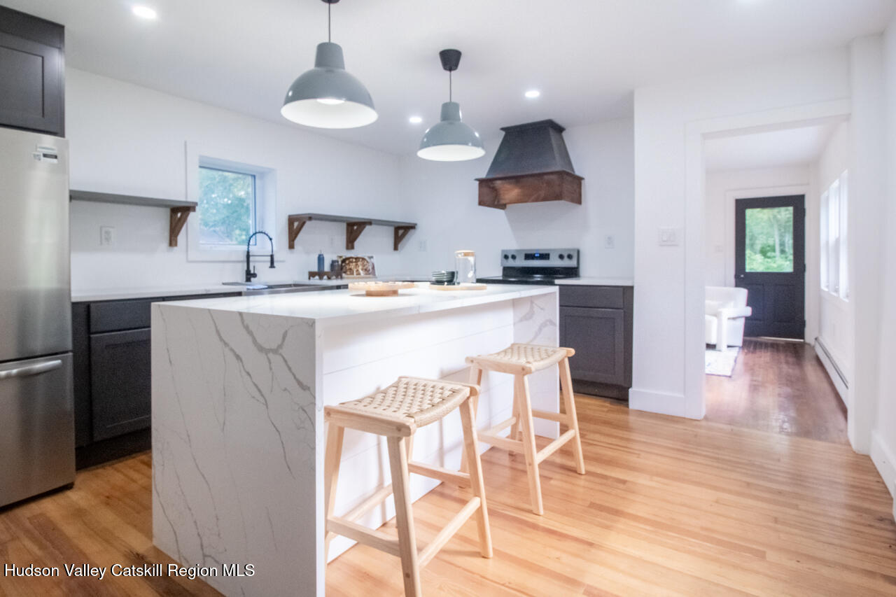 10 State Rte 55 Napanoch, NY 12458 - Photo 22 of 42 a kitchen with stainless steel appliances granite countertop a sink a stove a refrigerator and a dining table with wooden floor