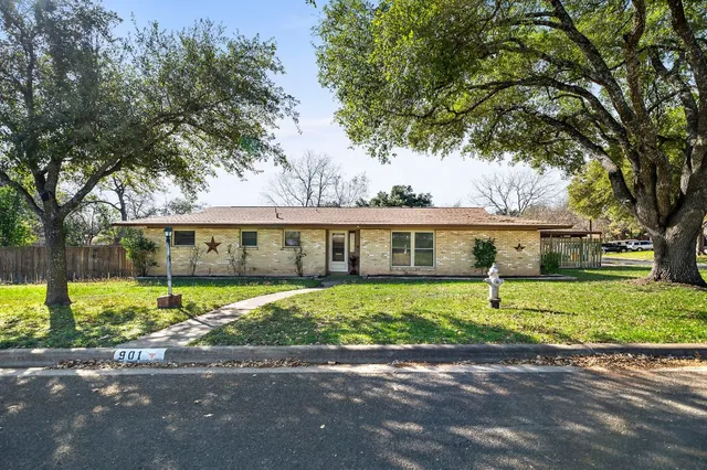 a view of a house next to a yard with big tree