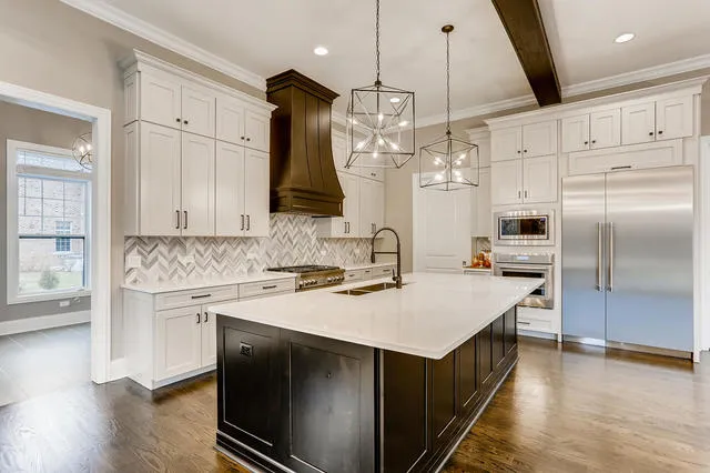 a kitchen with a sink stainless steel appliances a counter top space cabinets and wooden floor