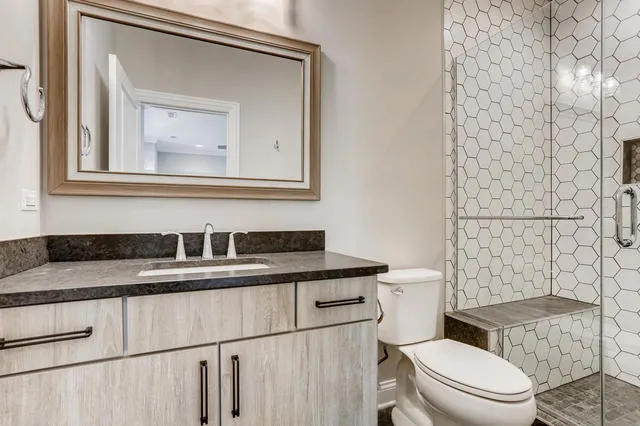 a bathroom with a granite countertop toilet sink and mirror