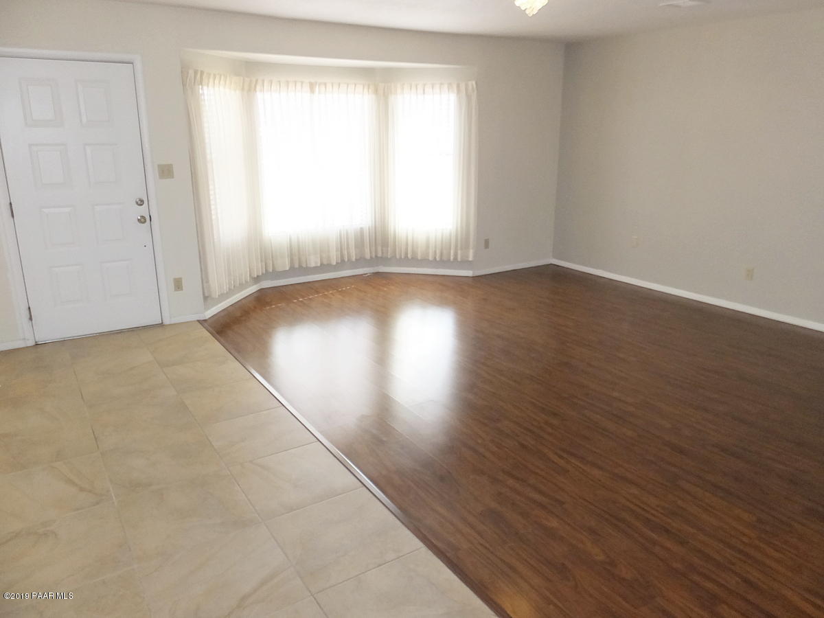 11950 Rawhide Ridge Dewey, AZ 86327 - Photo 3 of 37 an empty room with wooden floor and windows with curtains