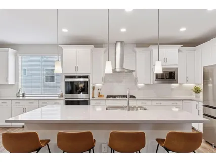 a kitchen with stainless steel appliances granite countertop a stove a sink a microwave a refrigerator and white cabinets