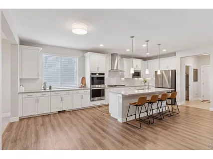 a kitchen with stainless steel appliances wooden floor and a refrigerator