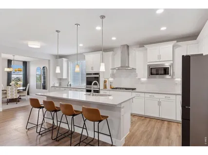 a kitchen with stainless steel appliances kitchen island granite countertop a stove a sink a microwave a dining table and chairs