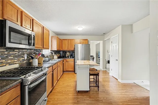 a kitchen with stainless steel appliances granite countertop a stove top oven a sink dishwasher and white cabinets with wooden floor