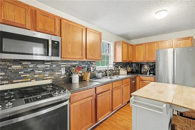 a kitchen with stainless steel appliances granite countertop a stove a sink dishwasher and a refrigerator