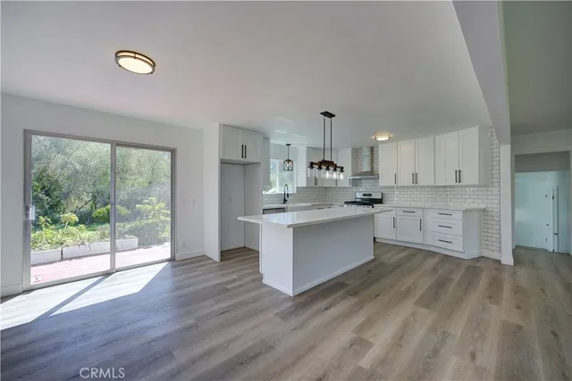 a large kitchen with stainless steel appliances granite countertop a stove a sink dishwasher and white cabinets with wooden floor